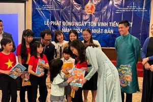 越南海外越南人国家委员会主任黎氏秋姮向孩子们赠送越南语教程。