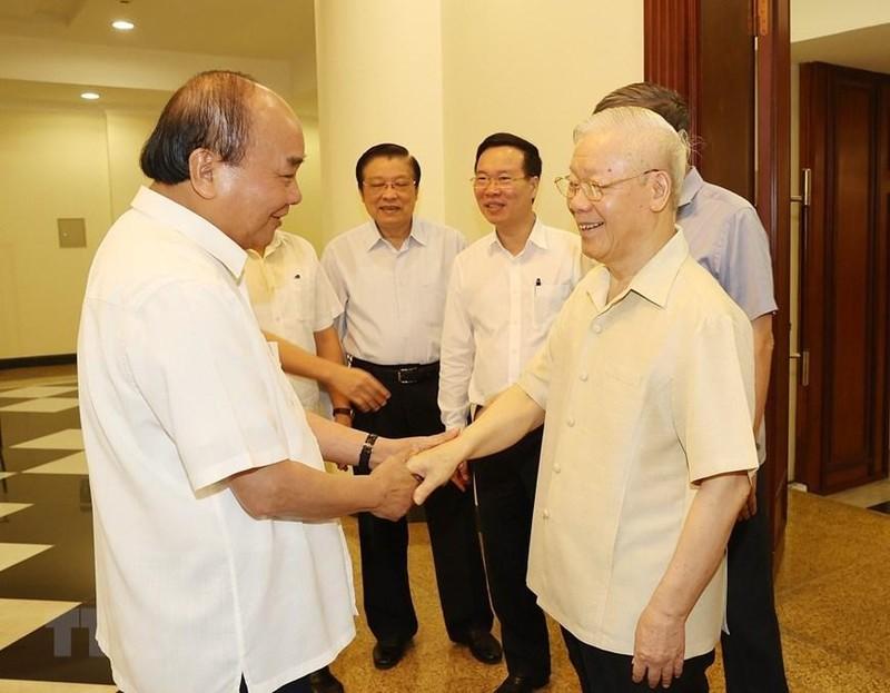 阮富仲总书记与与会的中央政治局委员、中央书记处书记握手。