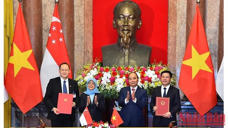 越南国家主席阮春福与新加坡总统哈莉玛•雅各布见证两国工贸部之间的合作备忘录签字仪式。