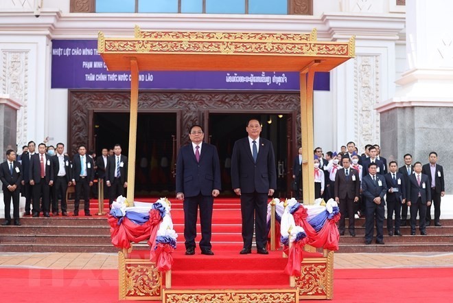 越南政府总理范明正与老挝总理宋赛• 西潘敦在欢迎仪式上听取越老两国国歌。