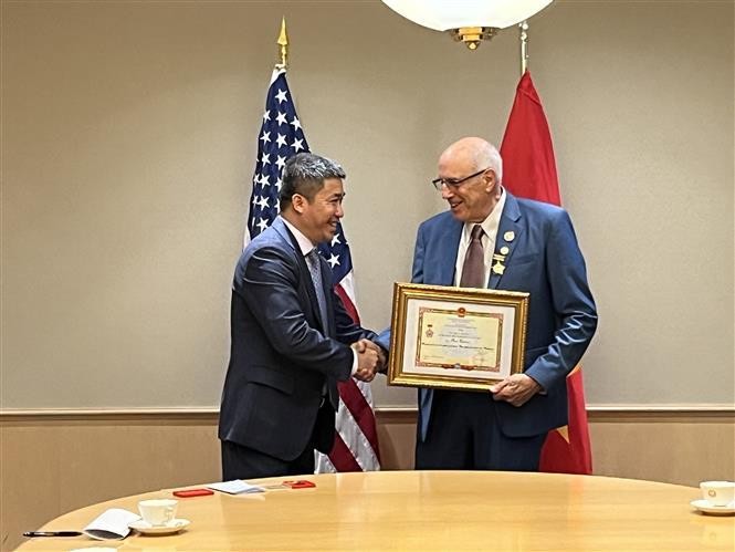 越南友好组织联合会副主席兼秘书长潘英山向罗恩·卡佛先生授予纪念章。（图片来源：越通社）