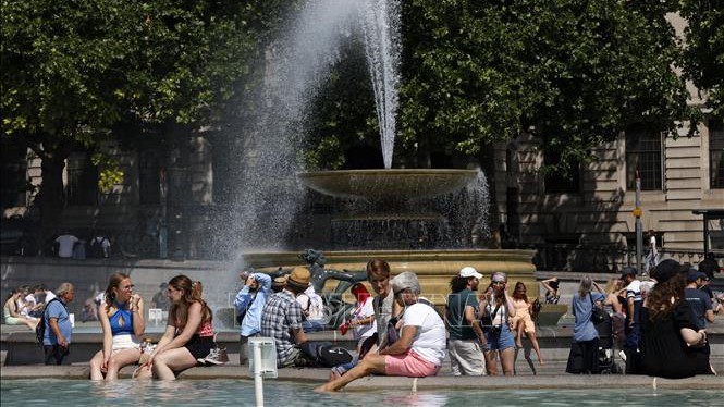 2022年6月17日，人们在英国伦敦特拉法加广场的喷泉旁纳凉。（图片来源：法新社/越通社）
