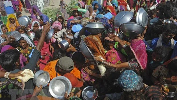 附图：在巴基斯坦信德省受洪水影响的地区的民众聚集领取粮食援助。（图片来源：法新社/越通社）