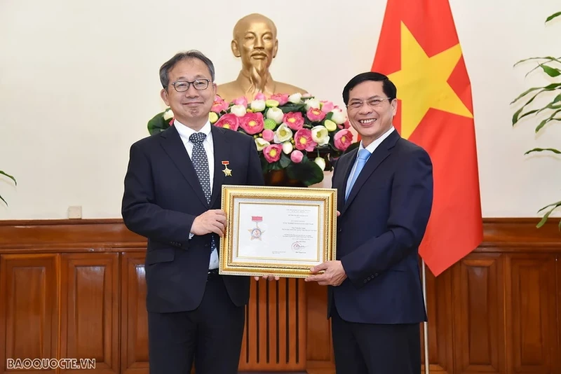 裴青山部长向山田贵雄大使授予“致力于越南外交事业”纪念章。（图片来源：国际报）