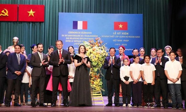 胡志明市人民委员会主席潘文买，法国驻胡志明市总领事格罗塞尔向在纪念仪式上表演的歌手和演员送花。