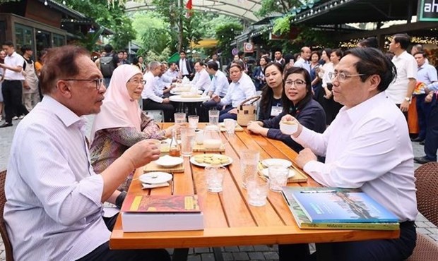 范明正总理、安瓦尔·易卜拉欣总理及两位夫人一边看书，一边欣赏越南林同省土桥一带闻名天下的阿拉比卡和罗布斯塔咖啡。