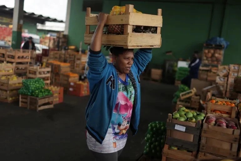 2022年8月30日在巴西里约，一名妇女手中拿着由商人捐赠的一盒蔬果。（图片来源：路透社）