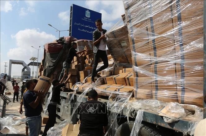 民众在加沙地带拉法口岸装卸人道主义援助物资。（新华社/越通社）