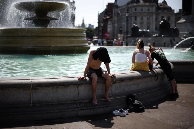 在创纪录的高温热浪期间，人们在英国伦敦特拉法加广场喷泉旁乘凉。（图片来源：路透社）