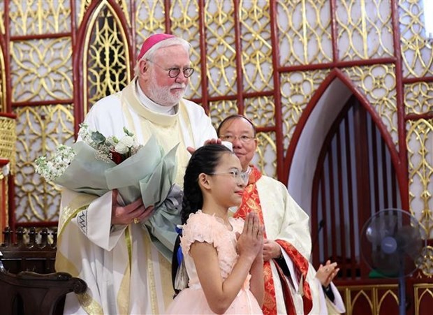 梵蒂冈外交部长保罗·理查德·加拉格尔（Paul Richard Gallagher）总主教接受越南儿童献上的鲜花。（图片来源：越通社）