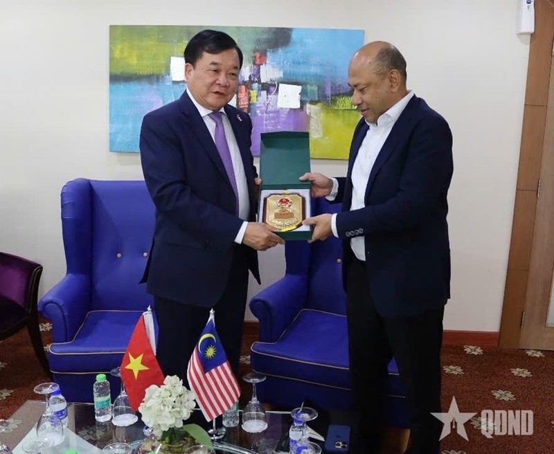 越南国防部副部长黄春战上将向马来西亚国防部副秘书长雅尼赠送纪念品。（图片来源：qdnd.vn）