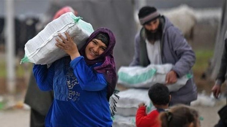 叙利亚难民在叙利亚迈赫迈迪耶镇的一个难民营接受援助。（图片来源：越通社）