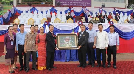 何英民同志向老挝国家大学领导赠送礼物。（图片来源：人民报网）