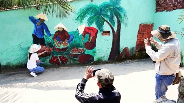 游客欣赏三青壁画村的墙画。