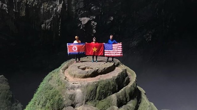 游客手拿着朝鲜、越南和美国国旗在韩松洞照相。