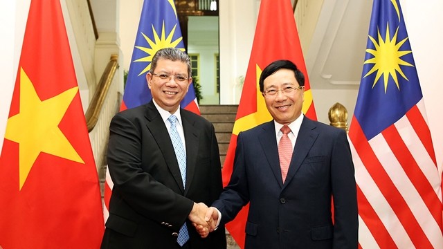 越南政府副总理兼外交部长范平明与马来西亚外交部长赛夫丁•阿卜杜拉握手。