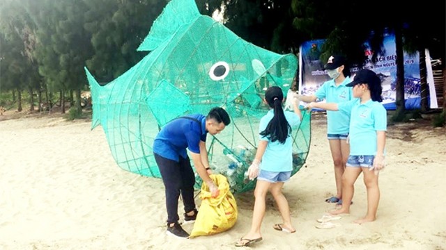 海河县的年轻团员和小朋友将塑料垃圾扔进海鱼模型。