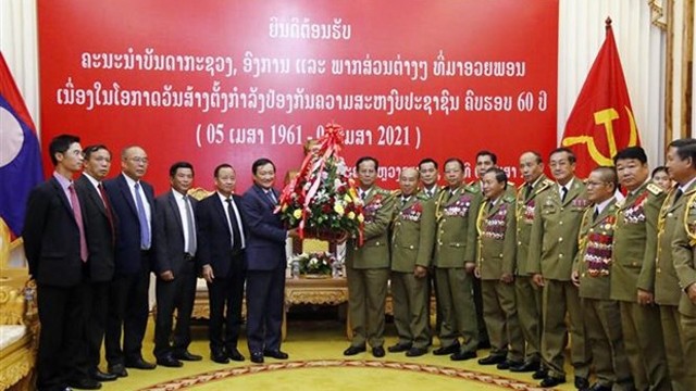 越南驻老挝大使阮伯雄向老挝人民革命党中央委员会委员、公安部副部长贡通·丰维吉中将赠送鲜花。