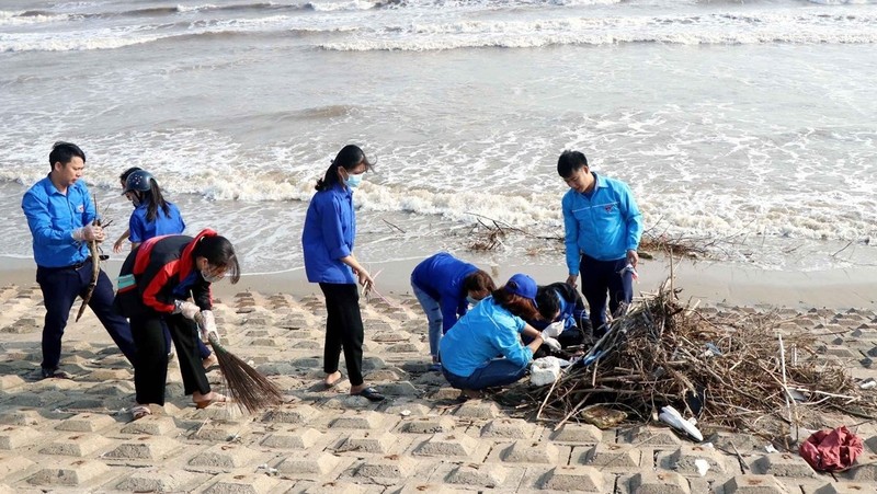 附图：越南青年打扫何静省海滩。