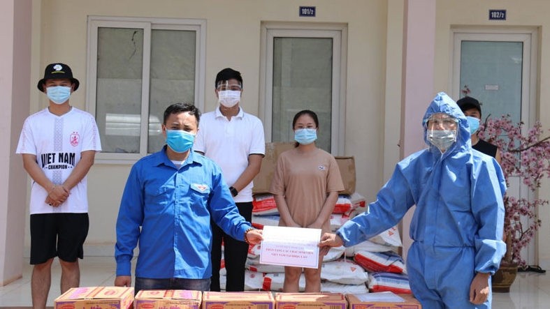 陈大胜同志向在老挝国家大学的越南留学生代表转交援助物品。（图片来源：人民报网）