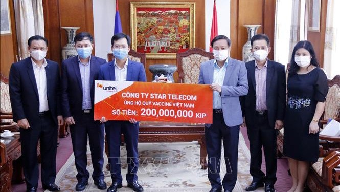 老挝星光电信公司总经理刘孟河向越南老挝大使阮伯雄移交为越南新冠疫苗基金捐赠的款项。（图片来源：越通社）