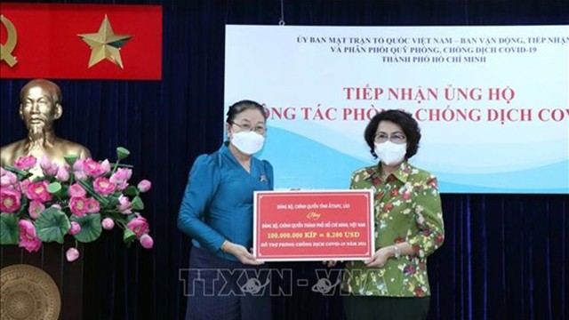 老挝驻胡志明市总领事乔米赛向苏氏碧珠女士交接援助款项。（图片来源：越通社）