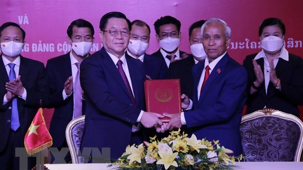 越共中央宣教部部长阮仲义同志（左）和老挝人民革命党中央宣训部部长坎潘·佩亚翁同志共同签署合作协议。