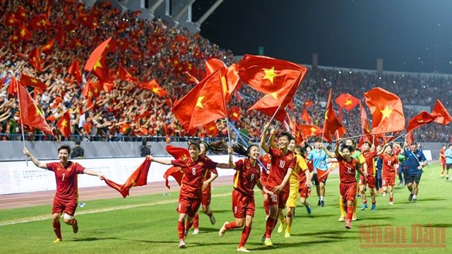 主裁判吹响了终场比赛的哨音，越南女球员手拿着国旗在体育场上庆祝胜利。